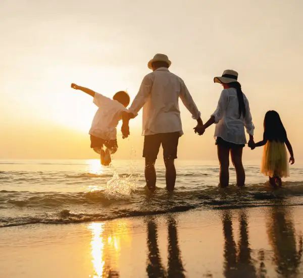 A family of 4 people at vacation enjoying on the beach during the sunset
